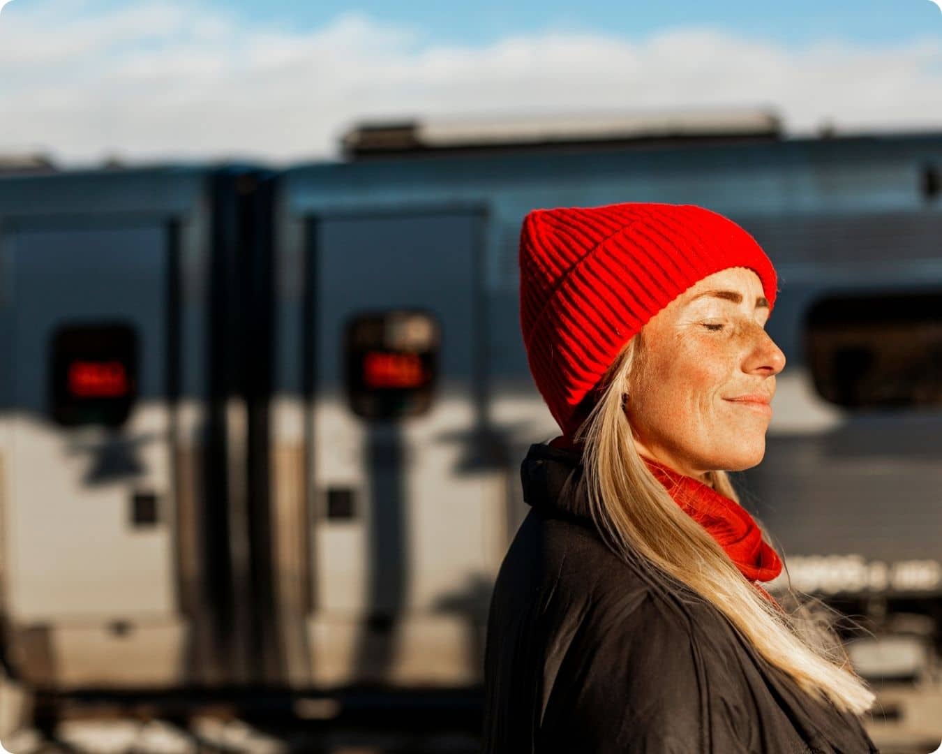 Få saken ut av verden. dame som smiler mot solen med rød lue