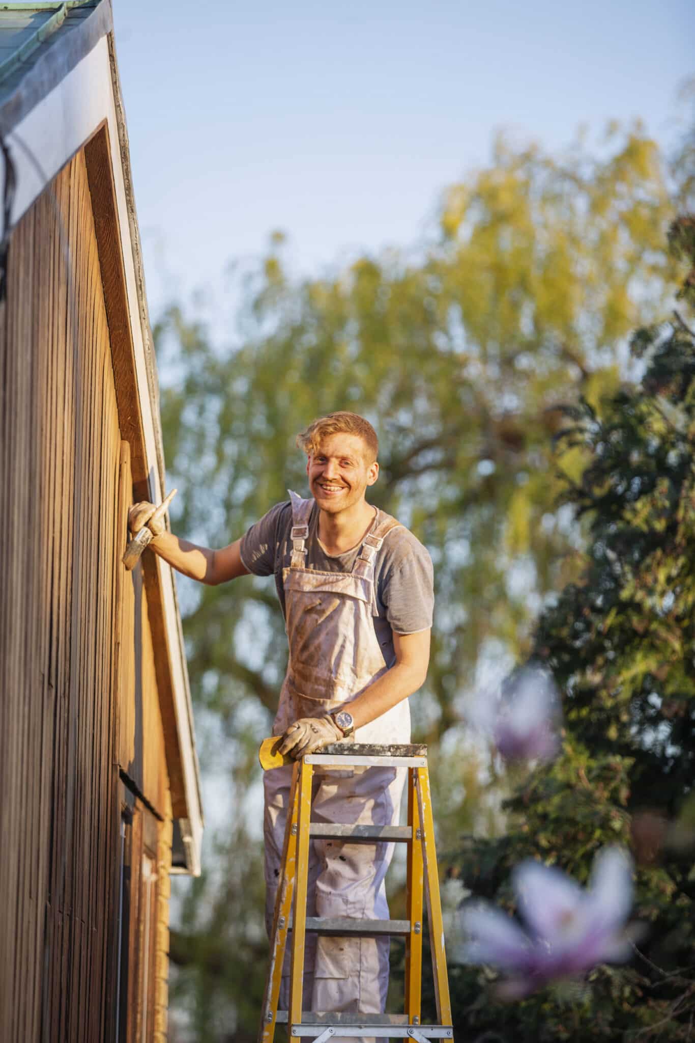 Portrait confident male painter on ladder painting home exterior